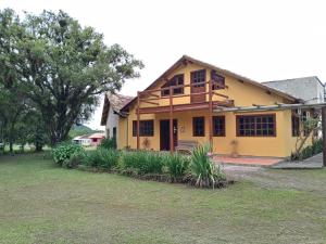 a yellow house with a porch and some plants at Pousada Malacara in Praia Grande