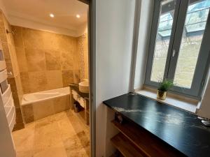 ein Badezimmer mit Waschbecken, Badewanne und Fenster in der Unterkunft Maison de Roche - Uzès Centre historique La Fenestrelle in Uzès + 27 Fotos