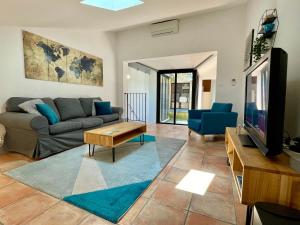 ein Wohnzimmer mit Sofa und Fernseher in der Unterkunft Maison de Roche - Uzès Centre historique La Fenestrelle in Uzès