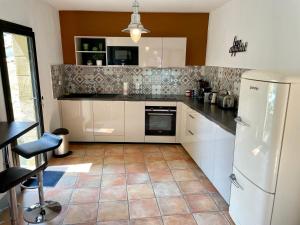 eine Küche mit einem weißen Kühlschrank und Fliesenboden in der Unterkunft Maison de Roche - Uzès Centre historique La Fenestrelle in Uzès