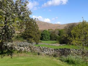 a stone wall in a field with mountains in the background at Lake District Log Cabins in Broughton in Furness