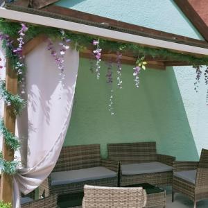 uma pérgola com uma cortina, cadeiras e flores em The Hawthornes Licensed Guest House em Knottingly