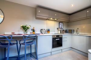 una cucina con armadi bianchi e sgabelli blu. di Bay Tree Cottage a York