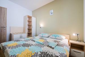 ein Schlafzimmer mit einem Bett mit einer bunten Bettdecke in der Unterkunft Apartmaji BANONIA " Štorkljin let " in Banovci