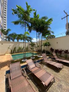 a group of chairs sitting next to a swimming pool at PALMAS EXPERIENCE - APARTAMENTO CONTEMPORÂNEO, vista serra, na quadra do shopping in Palmas