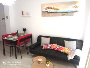 a living room with a black couch and a table at Vuestro apartamento del Sur in Fuengirola
