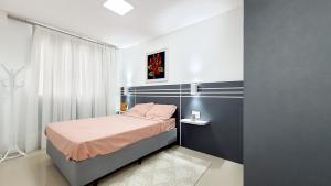 a small bedroom with a bed with pink sheets at Residencial Renata - Apartamento na Praia de Palmas - 3 dormitórios a 300m da Praia in Governador Celso Ramos