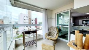 a living room with a table and a balcony at Residencial Renata - Apartamento na Praia de Palmas - 3 dormitórios a 300m da Praia in Governador Celso Ramos