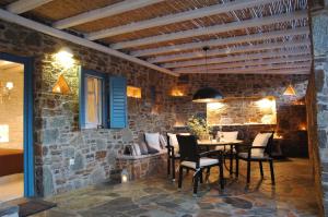 a dining room with a table and chairs and a stone wall at Chez Semiramis Aegean Pearl House for 8 persons 5'min from the beach in Serifos Chora