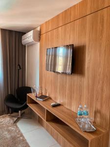 a room with a television on a wooden wall at Apart-hotel Granja Brasil Itaipava in Itaipava