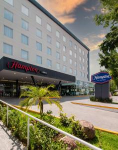 阿瓜斯卡連特斯的住宿－Hampton by Hilton Aguascalientes Downtown，一座酒店大楼,前面有棕榈树