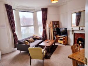 uma sala de estar com um sofá, uma mesa e uma televisão em Bright, character 3 bed Apartment: 7 mins walk to sea em Portsmouth