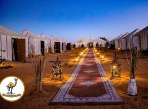 a row of tents in a desert at night with lights at Your magic camp in Merzouga