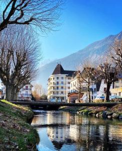 ein großes Gebäude neben einem Fluss mit Gebäuden in der Unterkunft Sport'Hotel-Aparthotel de Milan in Le Bourg-dʼOisans