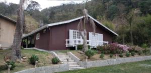 une maison rouge avec des fenêtres blanches et une cour dans l'établissement Casa Grande da Montanha - Sítio Pasangas, à Santo Antônio do Pinhal