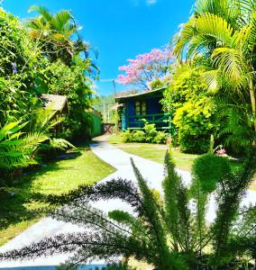 un jardín con palmeras y una casa en Mandala Camping Pousada, en Florianópolis