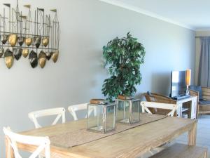 mesa de comedor con sillas blancas y maceta en Beachfront House - Hermanus Whale View en Hermanus