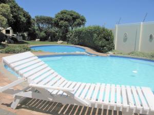 uma espreguiçadeira branca ao lado de uma piscina em Beachfront House - Hermanus Whale View em Hermanus