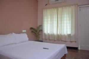 a bedroom with a white bed and a window at Hotel Ferreira Resort in Lonavala