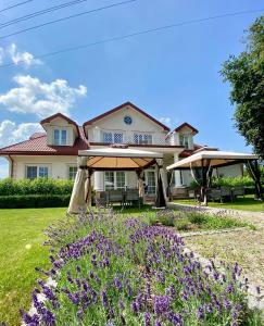 une maison avec des fleurs violettes dans la cour dans l'établissement Miód Lawenda, à Biardy