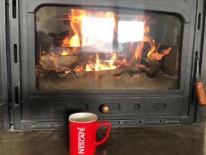 a red cup of coffee next to an open fireplace at LUX Villa Mavrovo in Mavrovo