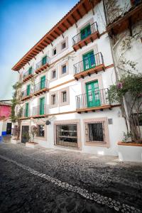 a large white building with green doors and windows at William Hotel Boutique De Diseño in Taxco de Alarcón