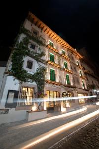 a large white building with green shuttered windows at night at William Hotel Boutique De Diseño in Taxco de Alarcón