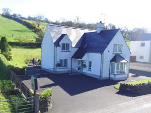 a white house with a black roof at Cloneymore Self Catering House in Cushendun