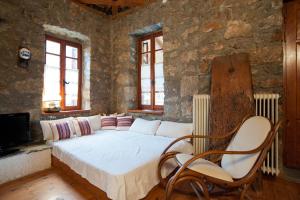 a bedroom with a bed with two chairs and a tv at MARIOLATA STONE HOUSE in Lílaia