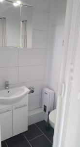 a white bathroom with a sink and a toilet at Pension Italia in Lübeck