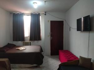 a bedroom with a bed and a couch and a television at Apto flat Antônio in Campos dos Goytacazes