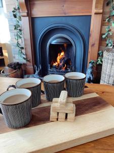 uma mesa de madeira com quatro taças e uma lareira em Claire's Townhouse, Aberdeenshire, 3 bedrooms em Oldmeldrum