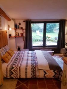 een slaapkamer met een groot bed en een groot raam bij Petit Gîte avec SPA en Ariege Montagnes des Pyrénées in Péreille