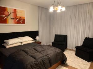 1 dormitorio con 1 cama y 1 silla en Apto lindo e novo no centro Gramado, en Gramado