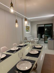 a dining room with a table with plates and wine glasses at Apto Beira-mar vista piscinas naturais in Porto De Galinhas