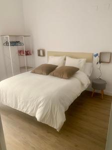 un grande letto con lenzuola e cuscini bianchi di Puerta de Caceres Apartamento 3 a Cáceres