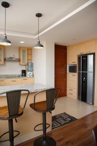 a kitchen with a black refrigerator and two chairs at Wanderlot - Departamento Leganza - Penthouse Lujoso in Riobamba