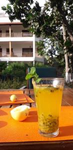 a glass of juice sitting on a table with a piece of fruit at Oasis Paul Residencial in Paul
