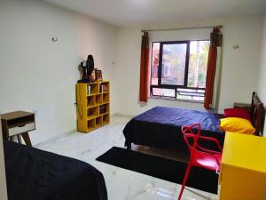 a bedroom with two beds and a red chair at Lindo Apartamento na Praia do Futuro in Fortaleza