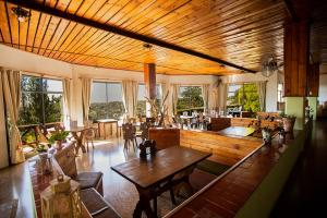 a living room with tables and chairs and windows at Hotel Panorama in La Cumbrecita