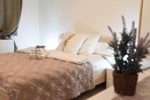 a bed with white pillows and a plant in a room at CIRIĆ APARTMANI in Vrnjačka Banja