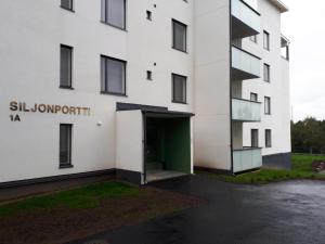 um edifício branco com uma porta verde num parque de estacionamento em Siljonportti Apartments em Rovaniemi