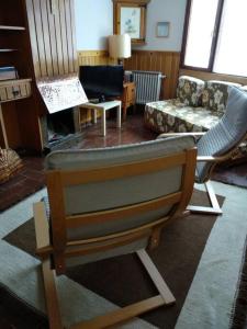 ein Wohnzimmer mit einem Stuhl und einem Sofa in der Unterkunft Peña del viento a pie de pistas estación San Isidro in Puebla de Lillo