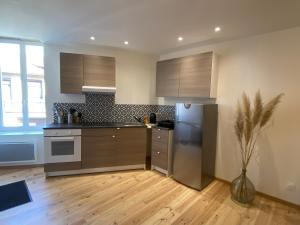 a kitchen with stainless steel appliances and a wooden floor at Cahors 62m2 - T3 neuf 4 étoiles certifié catégorie Prestige - le Bartassec - wifi - parking in Cahors