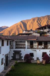 ein weißes Gebäude mit einem Berg im Hintergrund in der Unterkunft Hana'q Hostel en el Valle sagrado, junto al rió Vilcanota in Urubamba