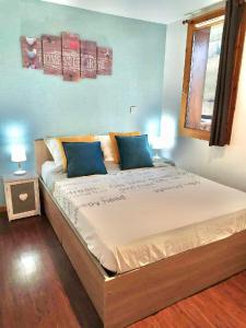 1 dormitorio con 1 cama grande con almohadas azules en SUPER-BESSE Charmant T2 Piscine chauffée & Parking couvert, en Besse-et-Saint-Anastaise