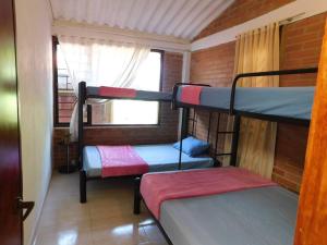Zimmer mit 3 Etagenbetten und einem Fenster in der Unterkunft Sauna y Jacuzzi en medio de la naturaleza in Cachipay