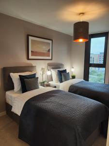 a bedroom with two beds and a large window at Luxury City Centre 2 bedroom apartment in Sheffield
