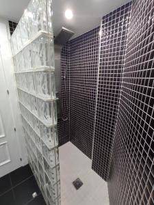 a bathroom with a black tiled shower with glass shelves at Bozocarro Descanso in Sallent de Gállego +9 photos