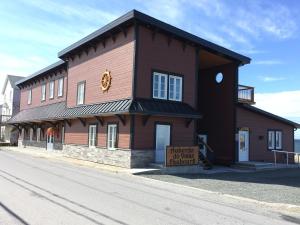 a brown building with a sign in front of it at Auberge du Vieux Faubourg in Sainte-Anne-des-Monts